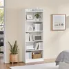 A white bookshelf filled with books and decorative items, placed next to a potted plant and a framed picture on the wall. Produktbild-Vorschau