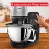A kitchen mixer is shown on a wooden countertop with a hand interacting with its control panel. Produktbild-Vorschau
