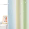 A close-up view of a curtain with a gradient color pattern and small star accents, next to a window with a framed picture on the windowsill. Produktbild-Vorschau