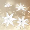 Four different stages of assembling a paper star decoration are shown against a bokeh background. Produktbild-Vorschau
