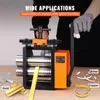 A person wearing gloves is operating a metal rolling mill machine. Various metal products like gold bars, silver bracelets, and copper rings are displayed around the machine. Produktbild-Vorschau