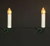 Two white LED candle lights with warm yellow flickering bulbs are clipped onto a green wire against a black background. Náhled obrázku produktu
