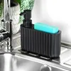 A black soap dispenser with a blue sponge holder sits next to a kitchen sink faucet. Produktbild-Vorschau