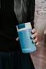 A person holding a blue Kambukka thermos. Náhled obrázku produktu