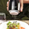 A person is using an electric pepper grinder over a plate of food. Náhled obrázku produktu