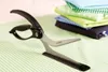 A pair of kitchen shears rests on a striped green and white tablecloth, with a stack of folded colorful fabrics in the background. Anteprima dell’immagine prodotto