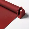 A close-up view of a red roller blind mechanism and fabric. Produktbild-Vorschau