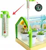 A mini greenhouse with plants and accessories, including a thermometer and compass, shown in a product marketing image. Podgląd zdjęcia produktu