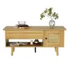 A light wood-tone coffee table with a rattan door and a drawer, displayed on a white background. Podgląd zdjęcia produktu