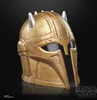A close-up studio shot of a golden helmet with silver spikes against a black background. Anteprima dell’immagine prodotto