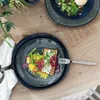 A close-up overhead view of two plates of food on a wooden table. Produktbild-Vorschau