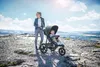 A woman pushing a stroller with a baby on a rocky cliff overlooking a valley. Náhľad obrázku produktu