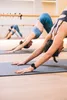 Three women in a yoga class performing a downward-facing dog pose. Náhľad obrázku produktu