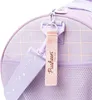 A close-up view of a purple duffel bag with a grid pattern and mesh accents. A pink strap with the text "Pusheen the Cat" is attached to the bag. Produktbild-Vorschau