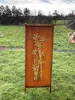 A rusted metal screen with a bamboo design stands in a grassy outdoor area. Produktbild-Vorschau
