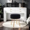 A black velvet stool with gold metal legs sits on a white rug in front of a white desk with a black hutch. Podgląd zdjęcia produktu