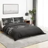 A bedroom scene with a bed made up with a black duvet cover and pillowcases featuring white text. Voir les images du produit