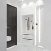 A modern entryway with a dark wood door, a white storage unit with a coat rack and drawers, and a white door. Produktbild-Vorschau