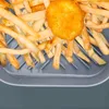 Close-up view of french fries and a single chicken nugget in an air fryer basket. Produktbild-Vorschau