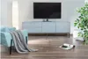 A modern living room with a TV stand, TV, armchair, and plant. Produktbild-Vorschau