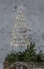 A wireframe Christmas tree decoration with lights is mounted on a textured wall, with evergreen branches in a wooden cart below. Podgląd zdjęcia produktu