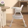A baby high chair is placed next to a dining table in a room. Podgląd zdjęcia produktu