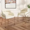 Two beige armchairs with gold legs are placed on a wooden floor in a room with white paneled walls and a painting on the wall. Podgląd zdjęcia produktu