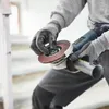 A person wearing work gloves is holding an angle grinder with a grinding disc attached. Produktbild-Vorschau
