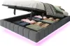A bed frame with its storage compartment open, revealing folded linens and blankets inside. The bed frame has integrated LED lighting at the base. Podgląd zdjęcia produktu