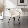 Two cream-colored chairs with black legs are placed on a gray tiled floor in a modern room. A tall dried grass plant in a white pot is to the left, and a wooden table with a glass on it is to the right. Produktbild-Vorschau