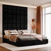 A black upholstered bed with plush pillows and a draped blanket, set against a large, dark square-paneled headboard. A modern pendant light hangs above. Anteprima dell’immagine prodotto