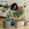 A woman is repotting a plant in a living room setting. Anteprima dell’immagine prodotto