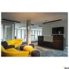 A modern office reception area with a yellow sofa, dark reception desk, and a large television screen. Produktbild-Vorschau