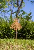 A metal fairy garden stake is shown in a garden setting with green plants and a blue sky. Produktbild-Vorschau