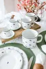 A table setting with porcelain cups, saucers, and plates, decorated with a floral pattern. Podgląd zdjęcia produktu