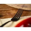 A close-up of a black fork on a placemat. Náhled obrázku produktu