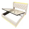 A white upholstered bed frame with a tufted headboard and LED lighting around the base and headboard. The bed frame is shown with the mattress support slats lifted, revealing storage space underneath. Anteprima dell’immagine prodotto