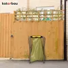 A yellow trash bag is held open by a metal stand in front of a wooden fence. Anteprima dell’immagine prodotto