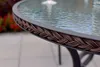 Close-up of the edge of a round glass-top table with a woven brown trim. Produktbild-Vorschau