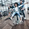 People having fun in an office environment, riding on office chairs. Produktbild-Vorschau