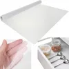 A collage showing a roll of white anti-slip drawer liner, a close-up of the liner texture held by a hand, and a drawer with kitchen items lined with the product. Voir les images du produit