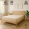 A bed with a fitted sheet is shown in a bedroom setting, with decorative elements and product feature icons. Produktbild-Vorschau