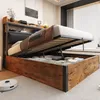 A bedroom scene with a bed frame open to reveal storage space underneath. A robot vacuum cleaner is on the floor in the foreground. Produktbild-Vorschau