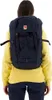 A person wearing a yellow sweatshirt and dark pants, with a blue backpack on their back. Náhled obrázku produktu