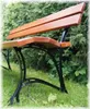 A wooden garden bench with black metal legs sits on a grassy lawn in front of a green hedge. Anteprima dell’immagine prodotto