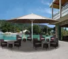 An outdoor patio area with a large umbrella and seating, overlooking a bay with boats. Produktbild-Vorschau