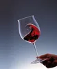 A hand holding a wine glass with red wine swirling inside. Podgląd zdjęcia produktu