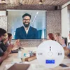 A group of people in a meeting room are looking at a projector screen while a carbon monoxide detector sits on the table. Produktbild-Vorschau