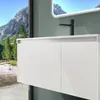A modern bathroom vanity with a sink and faucet, set against a backdrop of a mountain landscape visible through a large window. Produktbild-Vorschau