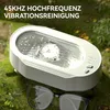 A white ultrasonic cleaner with water is placed on moss and grass, next to a pair of glasses. Produktbild-Vorschau